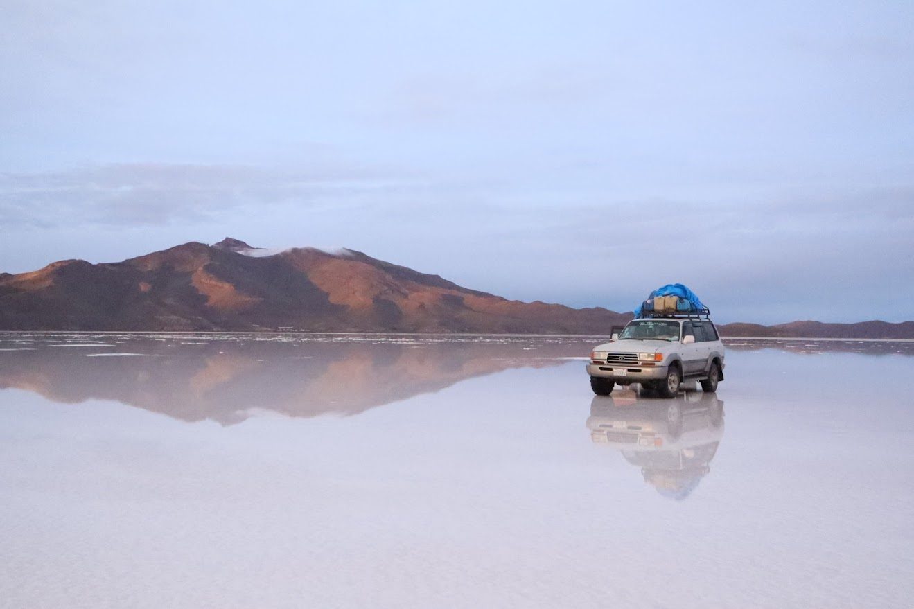 4x4 reflected on the Salar de Uyuni at dawn